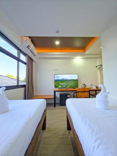 ein Hotelzimmer mit zwei Betten und einem Fernseher in der Unterkunft SANDB Hotel in Ko Phangan