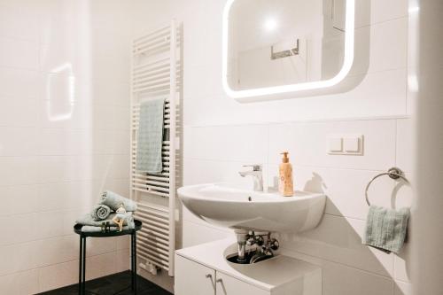 a white bathroom with a sink and a mirror at Wohnen bei frau tinz - Apartment - Bahnhof- und Zentrumsnähe in Neunkirchen