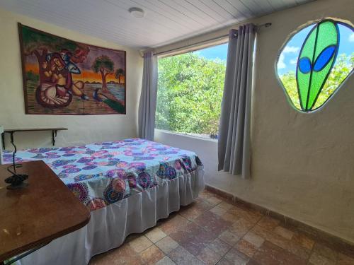 a bedroom with a bed and a large window at Bela Oyá Casa Hostel in Vale do Capao