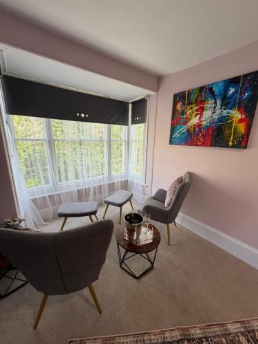 a living room with chairs and a large window at The Cleave Inn in Lustleigh