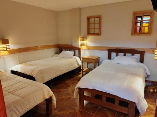 a room with two beds and two tables in it at Alma Andina Lodge in Huaraz