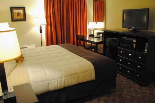 a hotel room with a bed and a flat screen tv at Village Inn Clemmons-Winston Salem, Trademark by Wyndham in Clemmons
