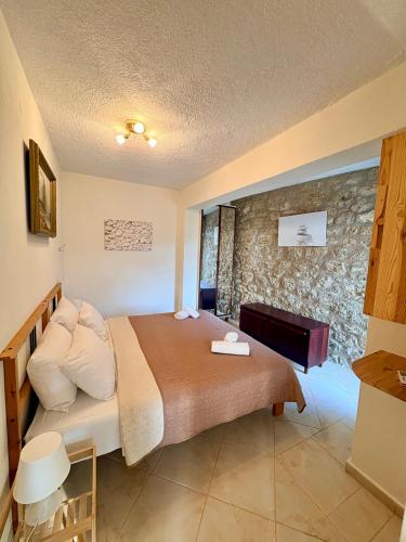 a bedroom with a bed and a stone wall at AGAPI Holiday House in Vouníon