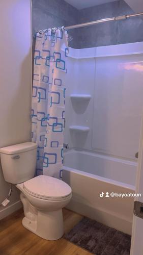 a bathroom with a toilet and a shower curtain at Cozy Urban Hideout in Saskatoon