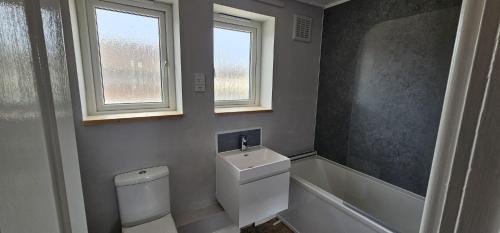 a bathroom with a toilet and a sink and a window at Leasowe House in Bidston