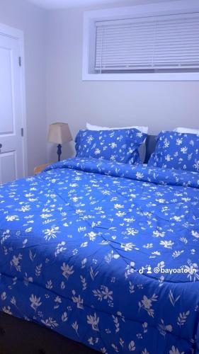 a blue bed with a blue blanket with white flowers at Cozy Urban Hideout in Saskatoon