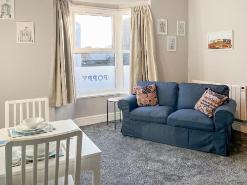 a living room with a blue couch and a window at Poppy - Uk49361 in Bridlington