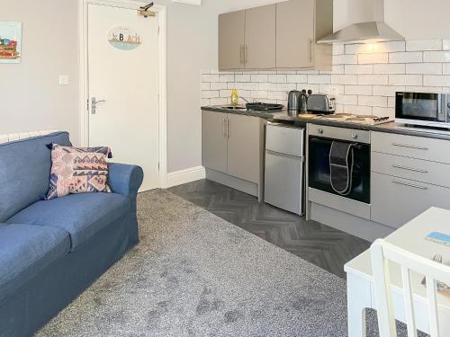 a living room with a blue couch in a kitchen at Poppy - Uk49361 in Bridlington