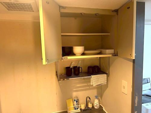 a kitchen with a sink and a shelf with dishes at KIYAZA City Sapporo CALIDO in Sapporo