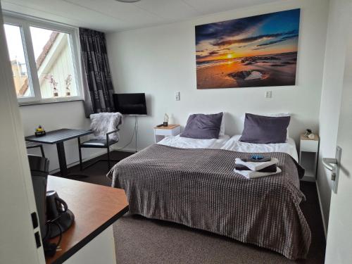 a bedroom with a bed and a desk and a chair at B&B Marijke in De Koog