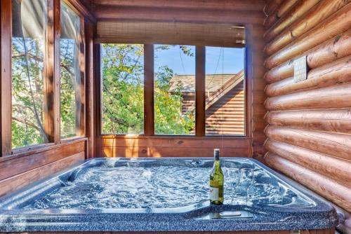 a hot tub in a log cabin with a bottle of wine at 2mils Dollywood, Resort Pool, King Bed, SL6 in Pigeon Forge