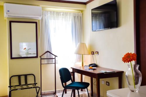 a room with a desk and a chair and a window at Hotel Gardenia Inn in San Salvador