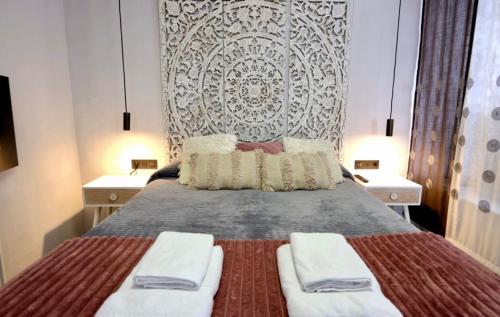 a bedroom with a bed with two white towels on it at Apartamentos De la Haya & Suite con Jacuzzi, junto al Teatro Romano in Mérida