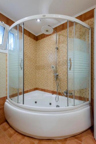 a bath tub with a shower in a bathroom at Maxim in Corfu