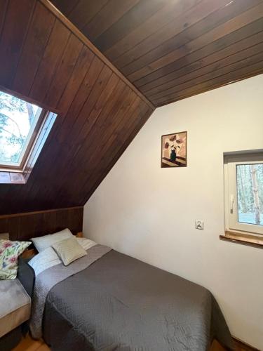 two beds in a attic room with a window at Kurort Mirowice-domek w lesie, z balią z jacuzzi i hydromasażem in Mirowice