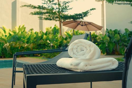 a pile of towels sitting on a table with an umbrella at Clatt Hotel in São João da Boa Vista