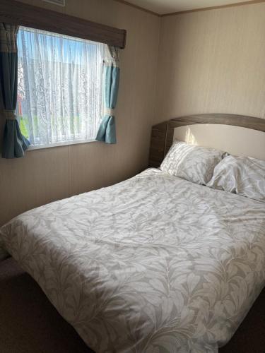 a bedroom with a white bed with a window at TLJ Caravan Hires in Mablethorpe