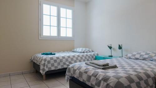 a bedroom with two beds and a window at Villa kréoli avec picine privée et cuisine extérieur pour 8 personnes in Saint-André