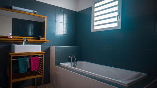a blue bathroom with a tub and a sink at Villa kréoli avec picine privée et cuisine extérieur pour 8 personnes in Saint-André