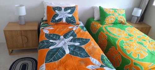a bedroom with two beds with orange and green comforters at Reureu Ocean Vistas in Arutanga