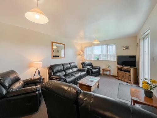 a living room with leather furniture and a flat screen tv at Uk47550 - Cairnsmore Cottage in Newton Stewart