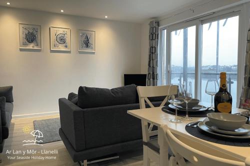 a living room with a couch and a table at Ar Lan Y Mor - Stunning 2 bed coastal apartment in Llanelli