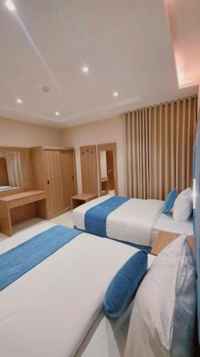 a hotel room with two beds with blue pillows at الديار الفاخرة - احد رفيدة in Ahad Rafidah