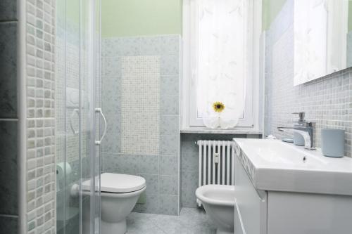 a white bathroom with a toilet and a sink at Dimora Stadio Biella in Biella