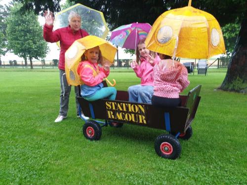 a group of children sitting in a toy car in the rain at Station Racour 'Magasin de la gare' in Landen