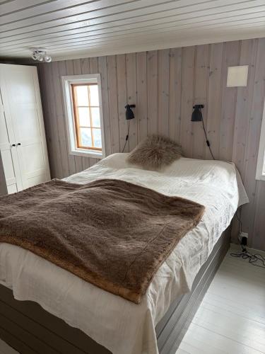 a bedroom with a large bed with a brown blanket at Cosy mountain cabin 875m near Turufjell, ski, fishing, hiking and quiet nature in Flå