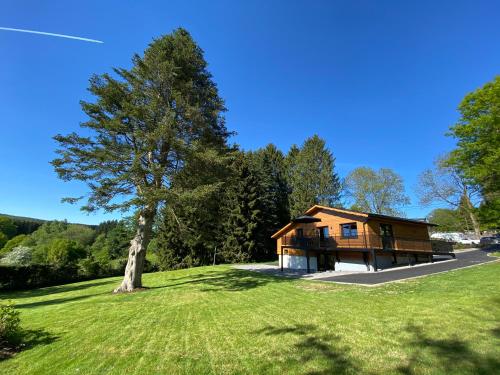 ein Haus auf einem Hügel mit einem Baum im Vordergrund in der Unterkunft La Roanneuse - Cosy Chalet in Francorchamps