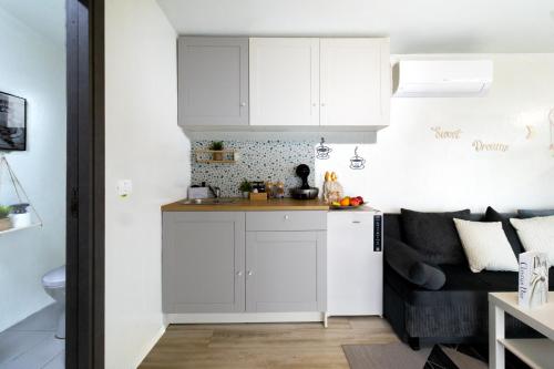 a kitchen with white cabinets and a couch in a living room at The HIDE - Dreamland in Boldeşti-Scăeni