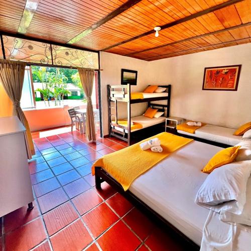 a bedroom with two beds and a balcony at Hotel campestre los gabrieles in Rivera