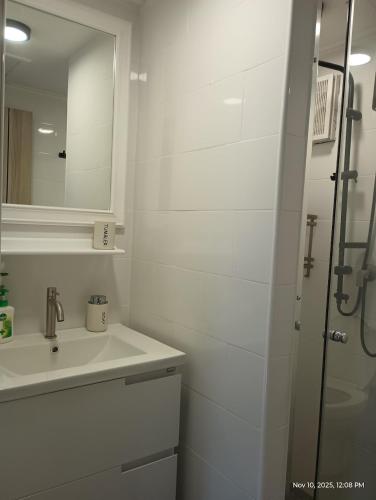 a white bathroom with a sink and a shower at Tree Top Beach Condo in Ban Pak Khlong Phe