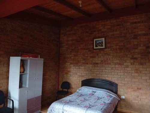 a bedroom with a bed and a brick wall at Casa Shaullo-Chalets in Los Baños del Inca