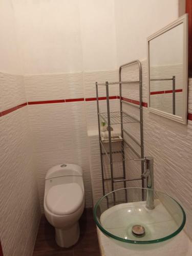 a bathroom with a toilet and a glass sink at Casa Shaullo-Chalets in Los Baños del Inca