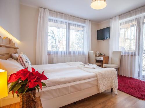 a bedroom with a white bed with red flowers on it at Willa Ryś in Zakopane