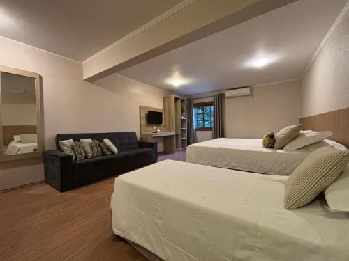 a hotel room with two beds and a couch at Pousada Stillo Gramado Centro - 300 metros da rua coberta in Gramado