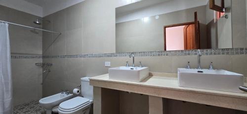 ein Badezimmer mit zwei Waschbecken, einer Toilette und einem Spiegel in der Unterkunft Mi Valle in Cafayate