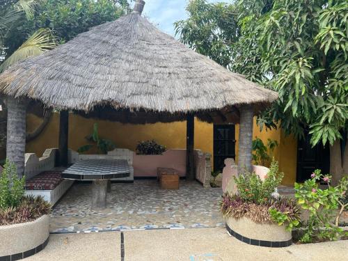 a small hut with a bench and a grass roof at Chez Aicha Ndangane in Ndangane