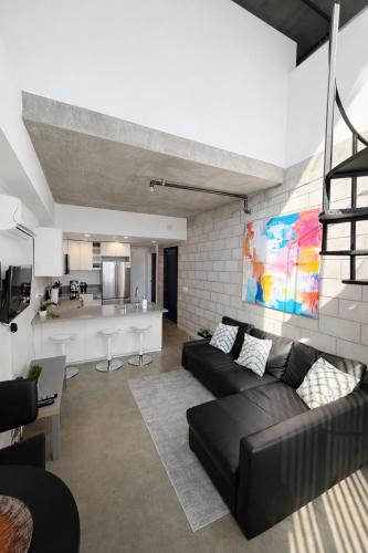 a living room with a couch and a kitchen at CasaViva Loft - Modern 2BR with Garage Parking, In-Unit Washer Dryer & ADA Access - Walk to Hillcrest, 5 Min to Gaslamp & North Park in San Diego