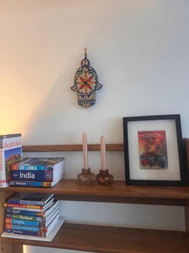 a shelf with books and two candles and a picture at Windsor Royal Retreat 2 bed 2 bath & private terrace in Windsor