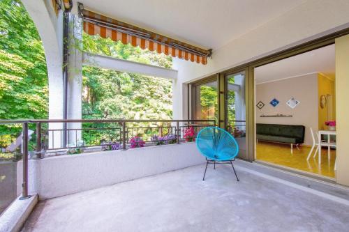 a blue chair sits on the balcony of a house at Maraini Elegante Apartment with Jacuzzi & Balcony - Happy Rentals in Lugano