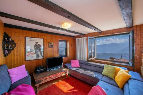 a living room with a couch and a large window at Chalet Cademario Lake-View 3BR Duplex - Happy Rentals in Cademario