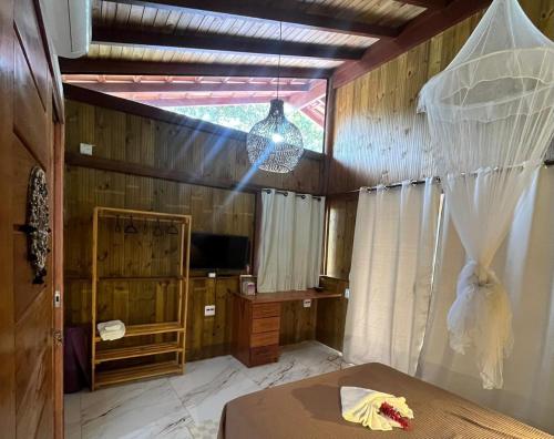 a room with a bed and a television and a window at Jeribucaçu bangalô in Itacaré