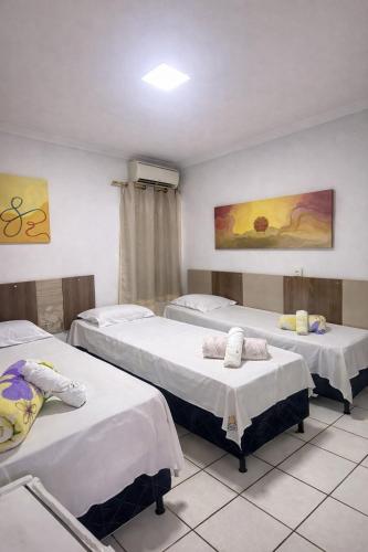 a room with three beds with white sheets at Hotel Shx Goiânia in Goiânia