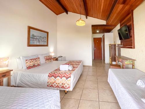 a hotel room with two beds and a tv at Pousada do Albatroz in Cabo Frio
