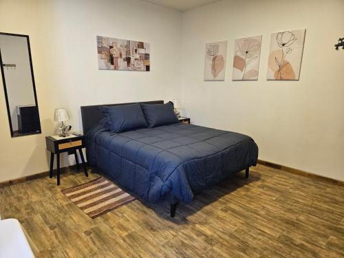 a bedroom with a bed with blue sheets and a table at Apartamentos TerraLoft in San Antonio