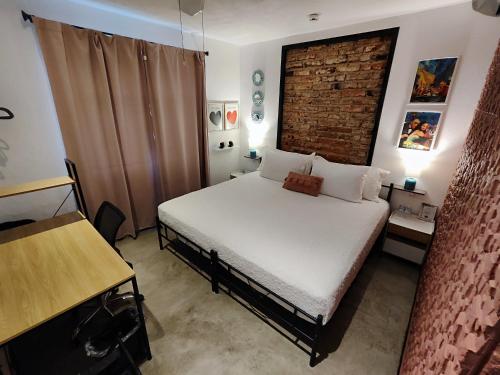 a small bedroom with a bed and a brick wall at Casa Aceves & Bueno Hotel Boutique in El Salto