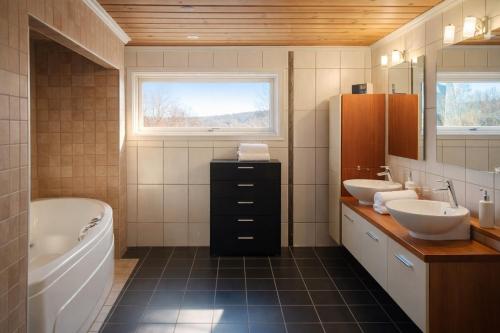 a bathroom with two sinks and a bath tub and a tubermott at KB - Villa sentrum Leknes in Vestvågøya